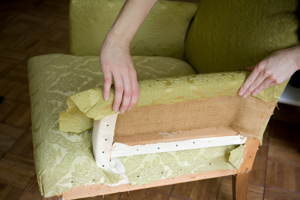 close-up of a woman reupholstering a green chair